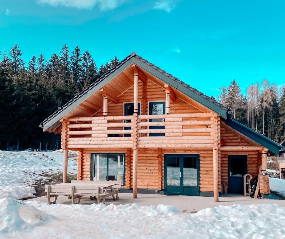 a log cabin in the snow with two picnic tables at Pur Natur! Wandern und Skifahren - Trahütti Premium Lodges in Trahütten