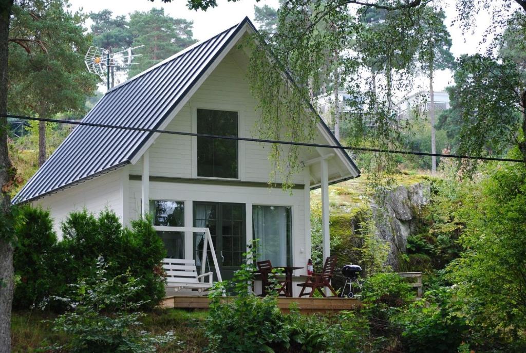 una pequeña casa blanca con un porche en el bosque en Anfasteröd Gårdsvik - badstugor med loft, en Ljungskile