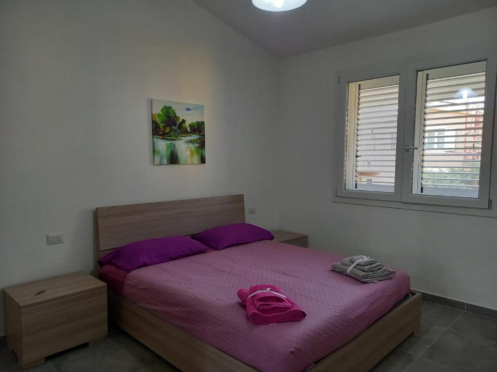 Un dormitorio con una cama con sábanas moradas y una ventana en Casa Beranu, en Maracalagonis