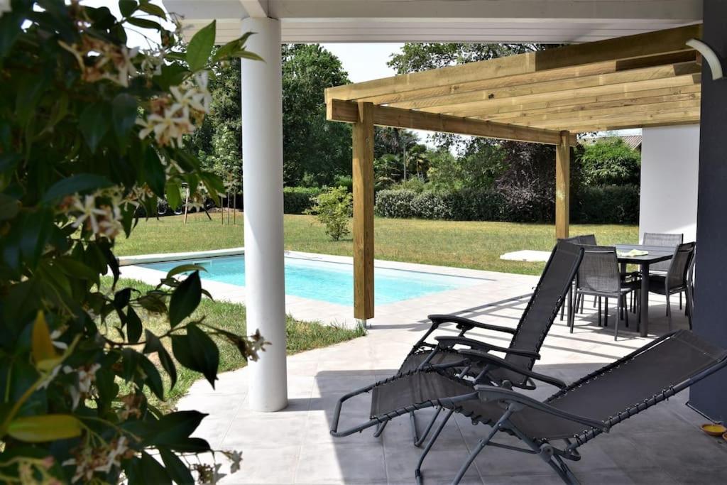 a patio with a table and chairs next to a pool at Calm house, swimming pool and garden in Bénesse-Maremne