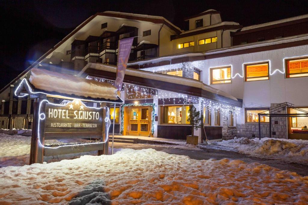 a building with christmas lights on it in the snow at Hotel San Giusto in Falcade