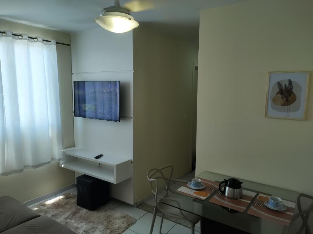 a living room with a table and a tv on a wall at Apê - Parque Industrial - SJC - SP in São José dos Campos