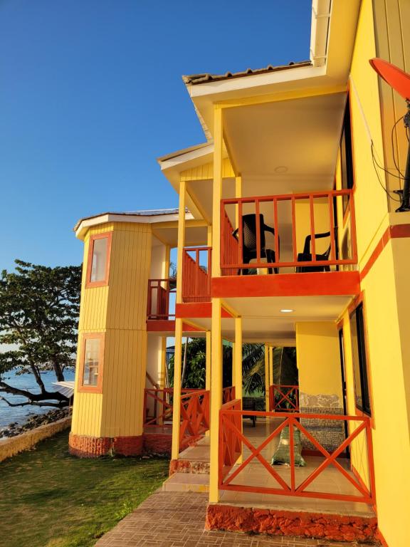 una casa gialla con balcone e oceano di Cabañas y Restaurante Miss Elma a Providencia
