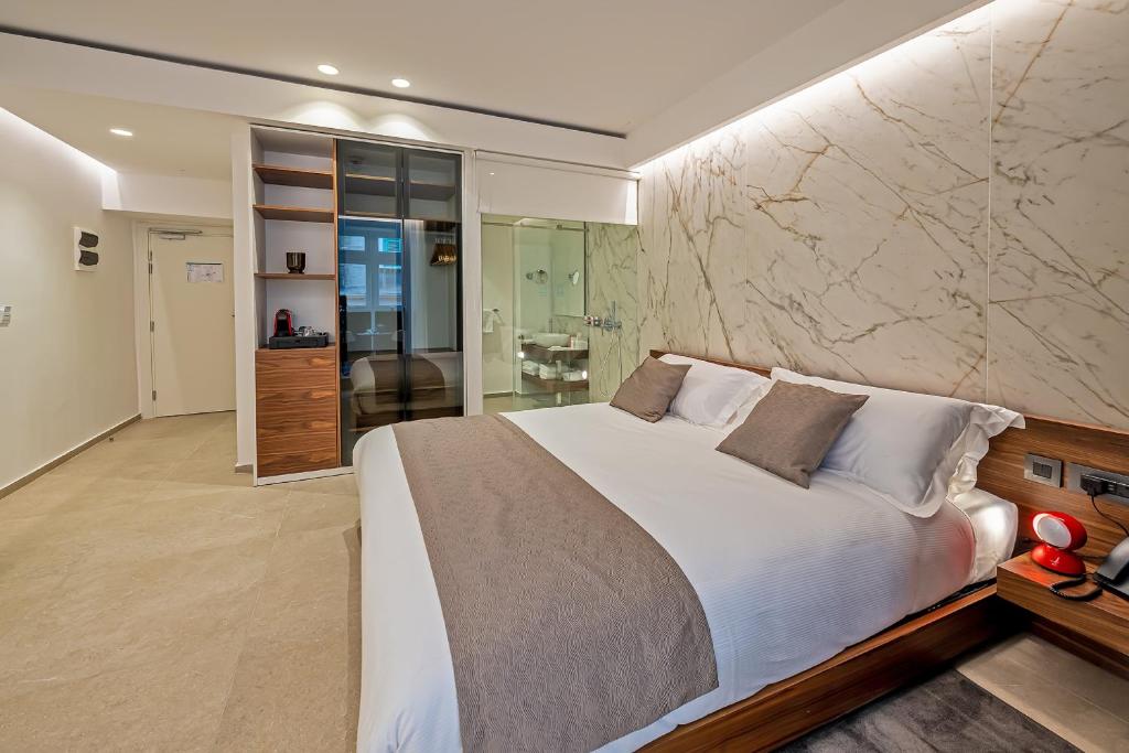 a bedroom with a large bed and a stone wall at The Capital Boutique Hotel in Valletta