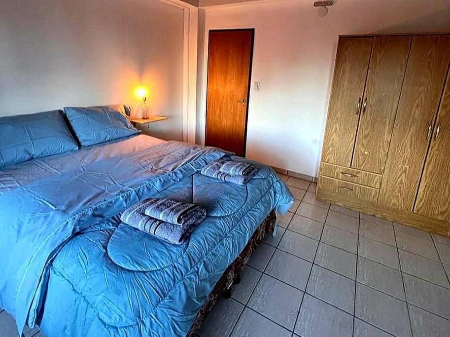 1 dormitorio con 1 cama con sábanas azules y armario en Ushuaia Torre Los Navegantes, departamento1, 2hab. en Ushuaia