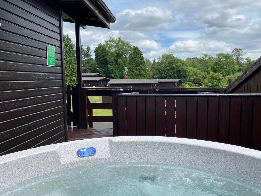 un jacuzzi en un patio trasero con una valla en Birch Lodge 14 with Hot Tub, en Newton Stewart
