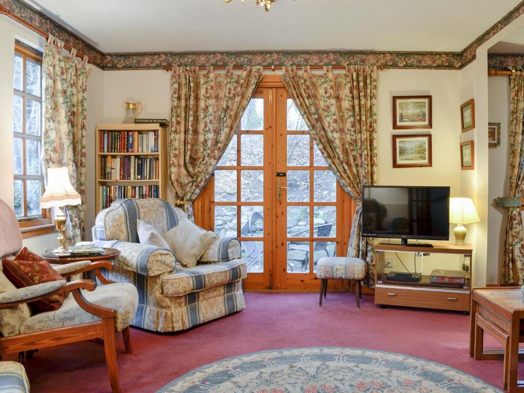 a living room with a couch and a tv at Toll Bridge Lodge in Banchory