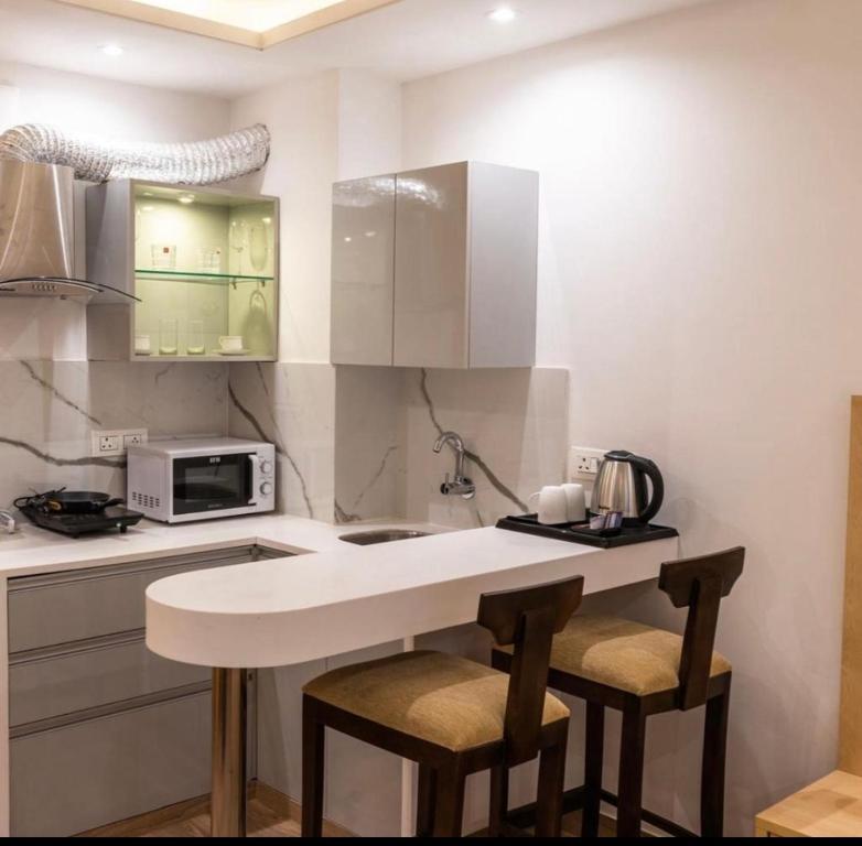 a kitchen with a counter with two bar stools at The Grand Anukampa Habitat Studio apartment in Jaipur