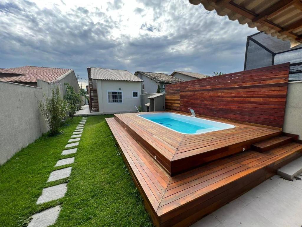 un patio trasero con piscina en una terraza de madera en Casa 4/4 com piscina. en Maricá