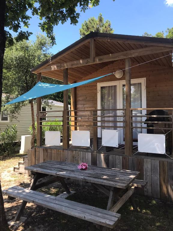 - une table de pique-nique et des chaises en face d'une cabine dans l'établissement Chris et Sabrina - Camping Les Viviers 4 étoiles, à Lège-Cap-Ferret