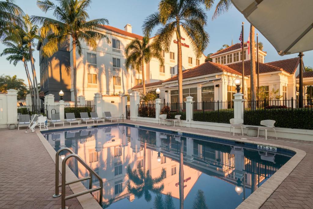 uma piscina em frente a um edifício com palmeiras em Hilton Garden Inn Boca Raton em Boca Raton
