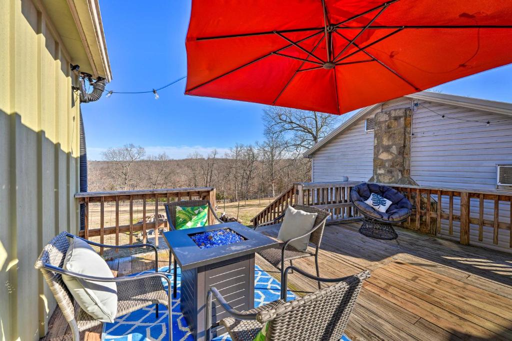 a table and chairs on a deck with a red umbrella at Boho Mountain Home Escape, Walk to Marina! in Mountain Home