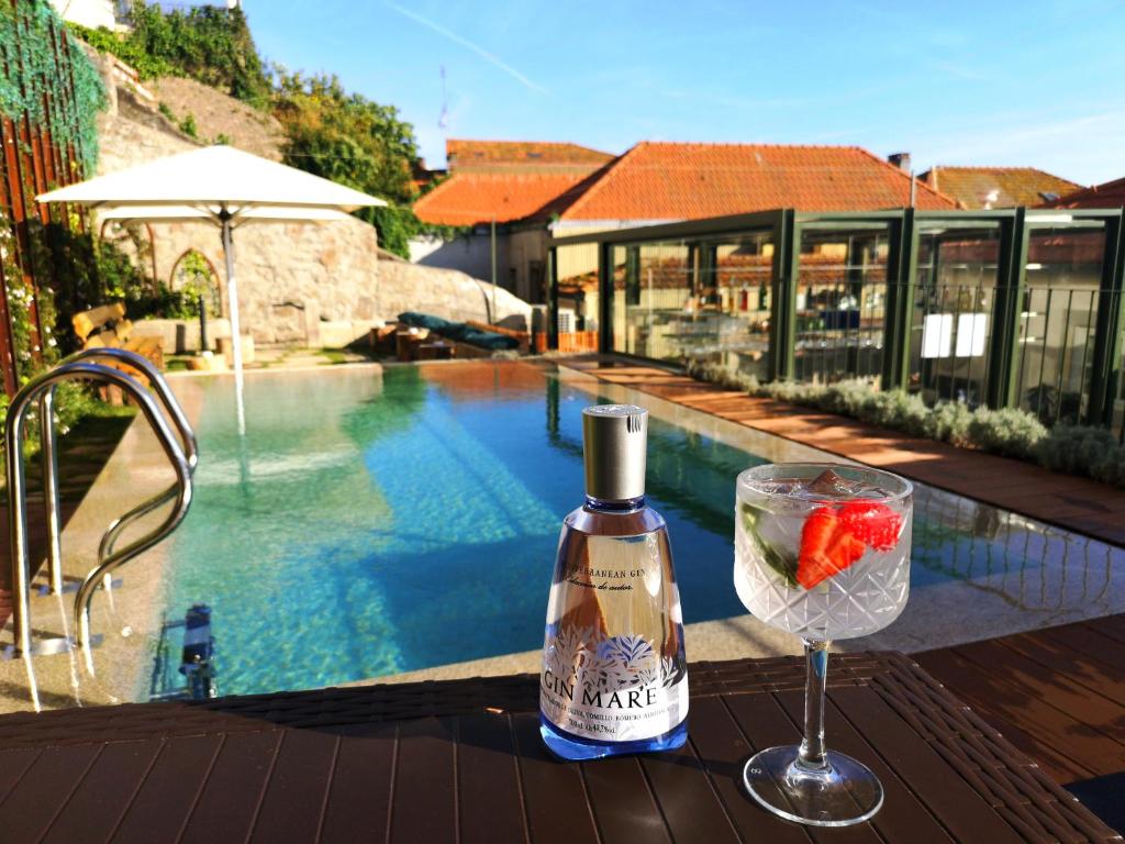 - une bouteille de vin et un verre à côté de la piscine dans l'établissement Porta Nobre - Exclusive Living Hotel, à Porto
