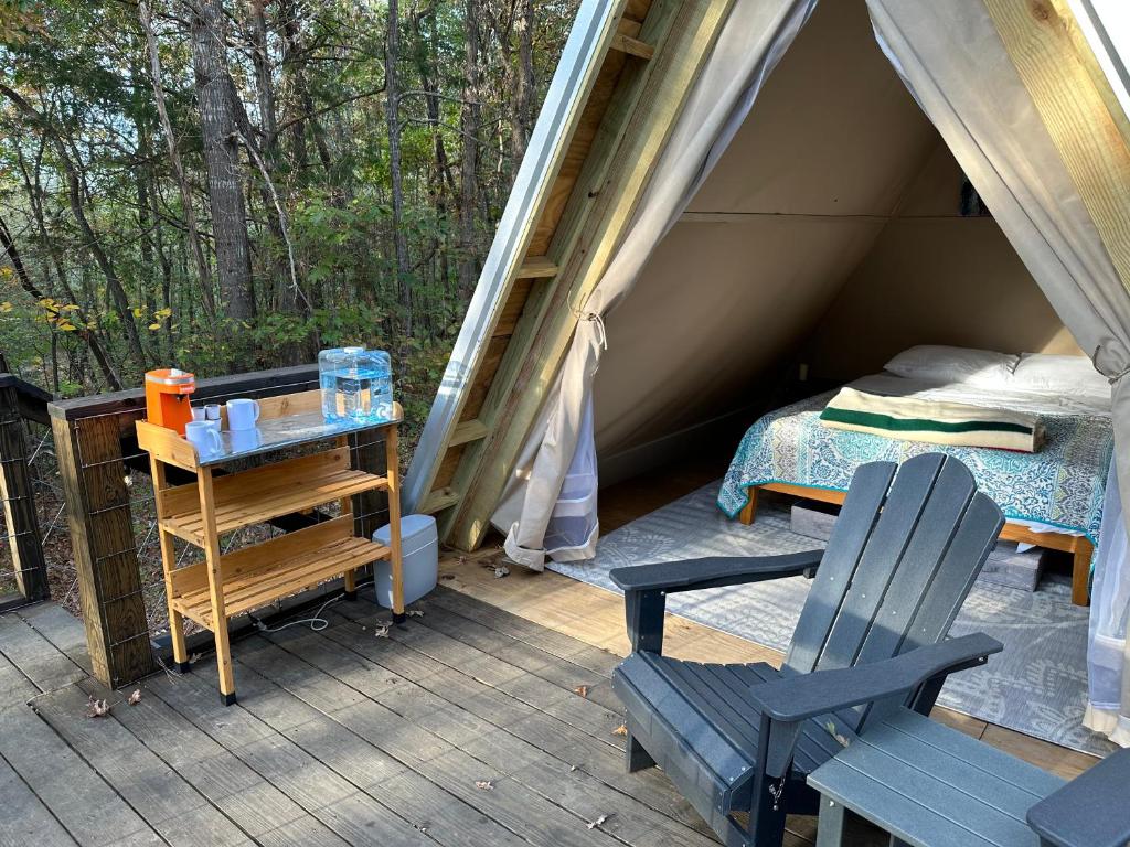 Tienda de campaña con cama y silla en la cubierta en Bohamia - Cozy A-Frame Glamp on 268 acre forest retreat, en Talladega