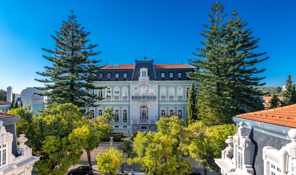 リスボンにあるPestana Palace Lisboa Hotel & National Monument - The Leading Hotels of the Worldの目の前に木々が植えられた白い大きな建物