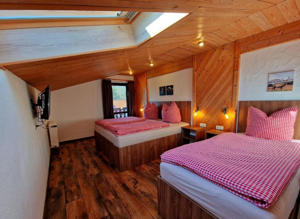 1 dormitorio con 2 camas en una habitación con techos de madera en Gästehaus Geist en Ruhpolding