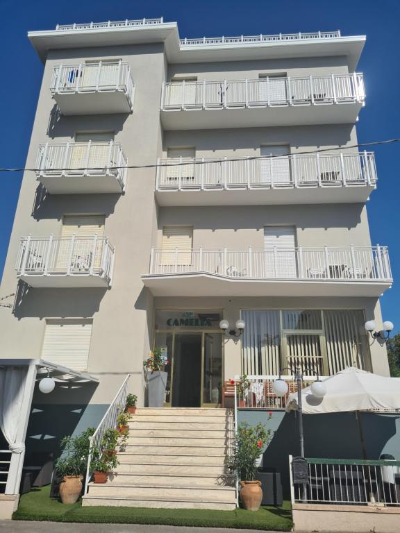 a building with white balconies and stairs in front of it at Hotel Camelia in Rimini
