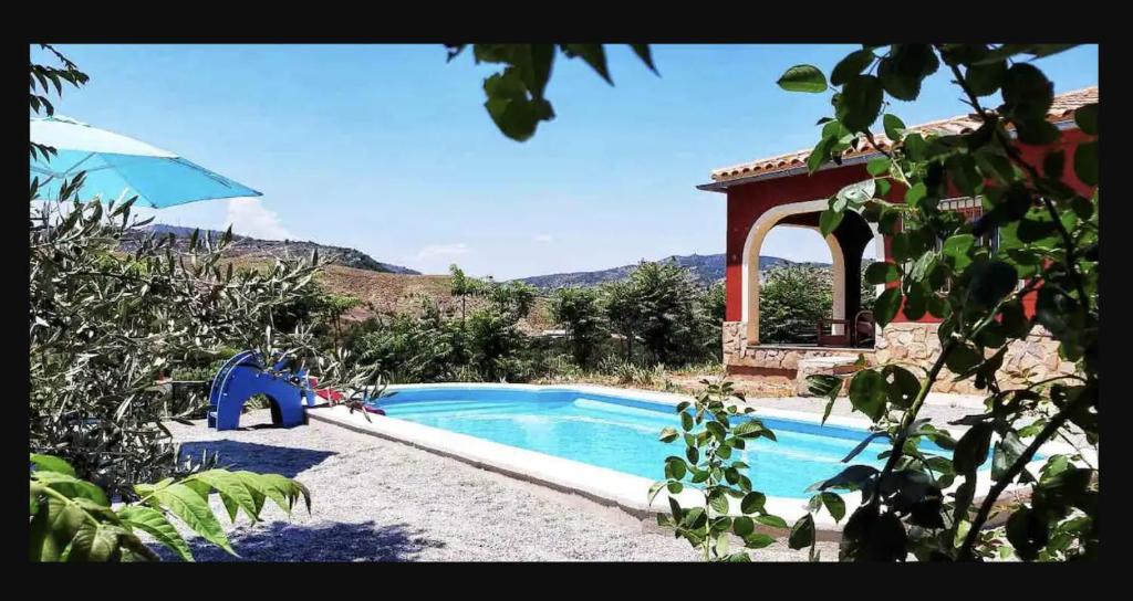 a swimming pool with an umbrella next to a house at Valley Views Full House Stargazing in Valencia in Ayora