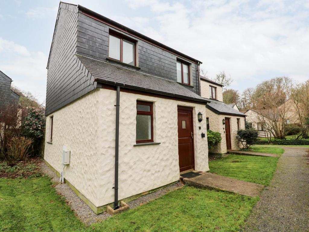 a small white house with a black roof at Surfers Retreat in Falmouth
