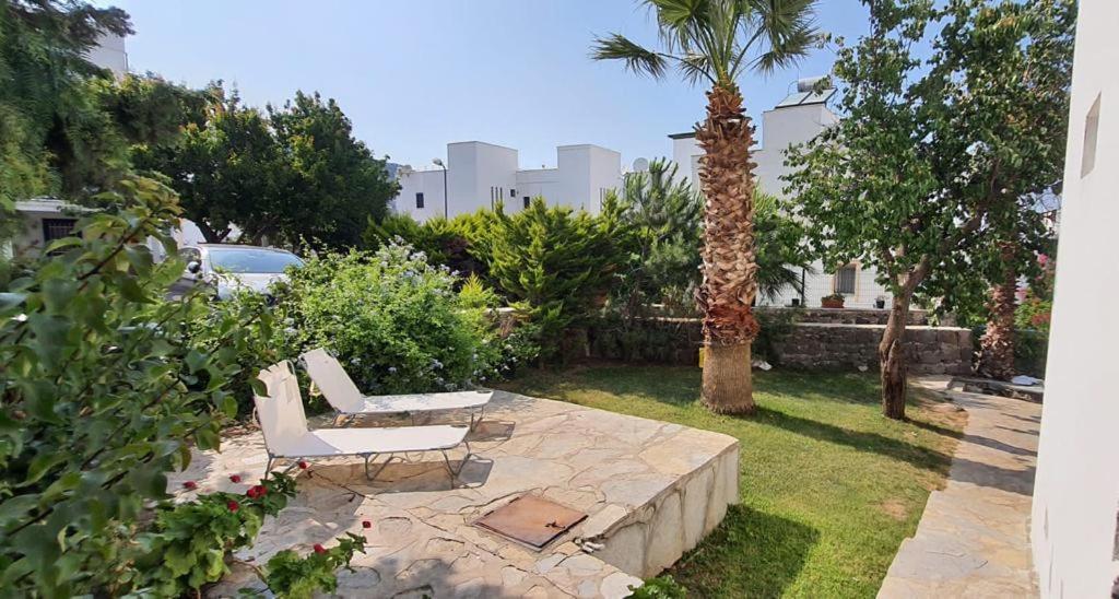 a patio with two white chairs and a palm tree at Bodrum Gundogan Full Sea View With Garden Triplex Villa in Bodrum City