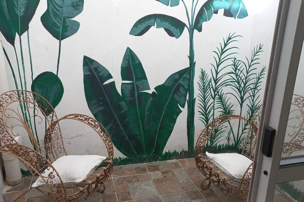 una habitación con 2 sillas y una pared con plantas en Departamento Costanera en Gualeguaychú