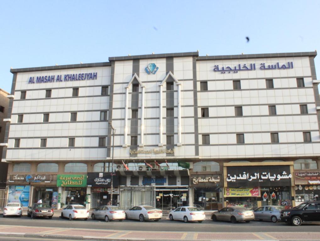 ein großes weißes Gebäude mit davor geparkt in der Unterkunft Al Massah Al Khalijiyah Furnished Units in Dammam