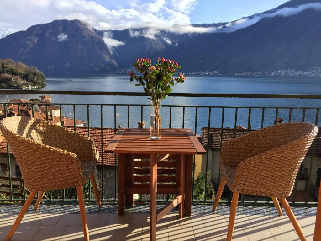 a wooden table with chairs and a vase of flowers on a balcony at Vista Azzurra in Sala Comacina