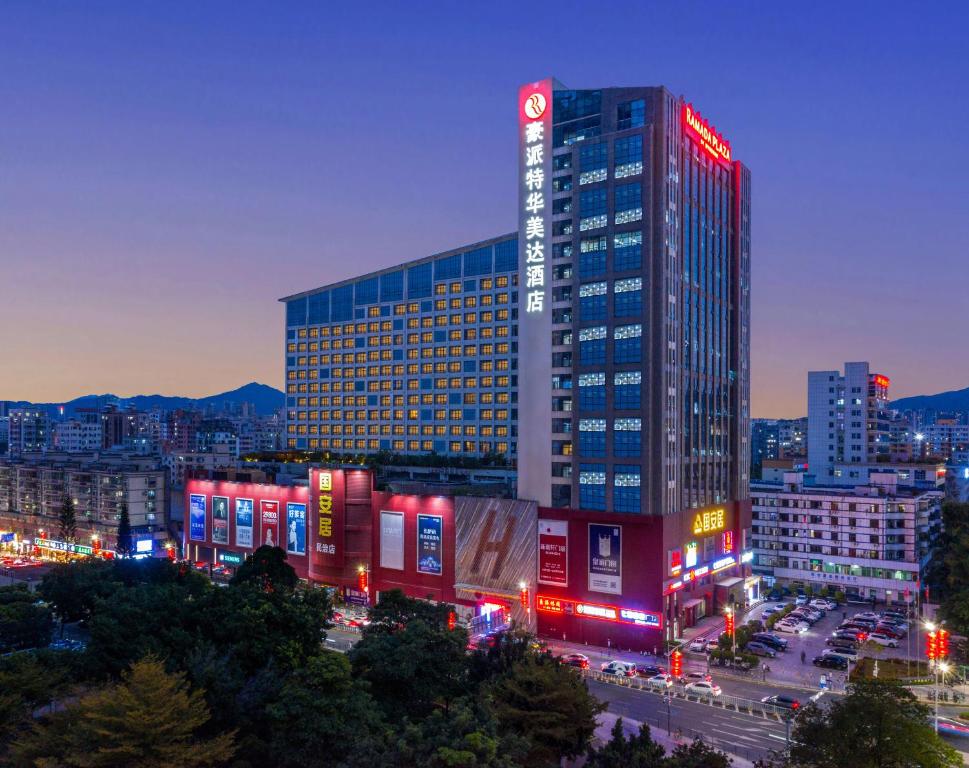 a tall building with red lights in a city at night at Shenzhen Ramada Plaza, North Railway Station in Shenzhen