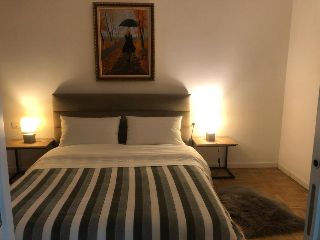 ein Schlafzimmer mit einem Bett mit zwei Lampen an zwei Tischen in der Unterkunft City Center Cute and Comfy Apartment - Ajia Apartments in Tirana