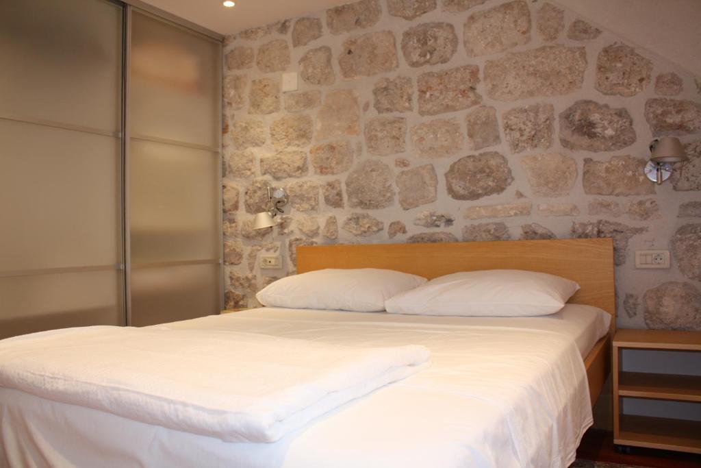 a bed in a room with a stone wall at Apartment Sorta in Dubrovnik