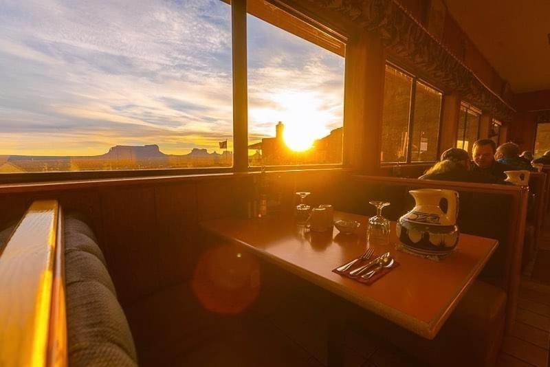 Goulding's Lodge في مونيومنت فالي: طاولة في مطعم مع غروب الشمس في الخلفية