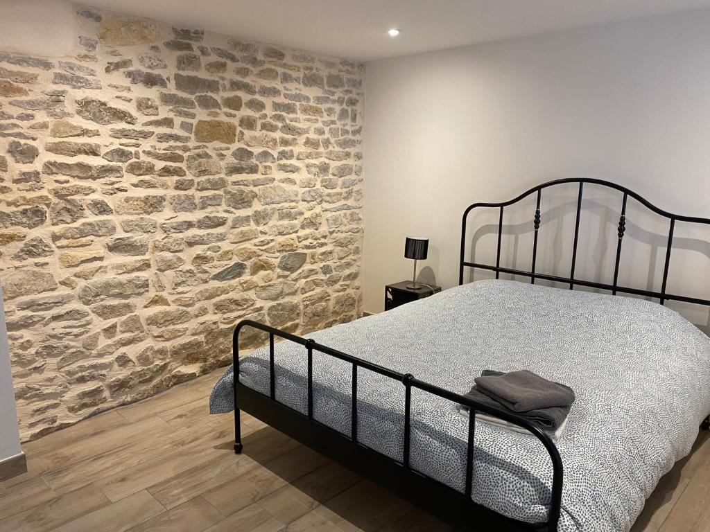 Cama en habitación con pared de piedra en Le Saint-Hilaire, en Saint-Hilaire-de-Brens