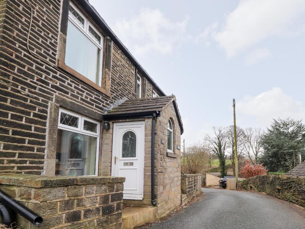a brick house with a white door on a street at Rivendell in Holmfirth