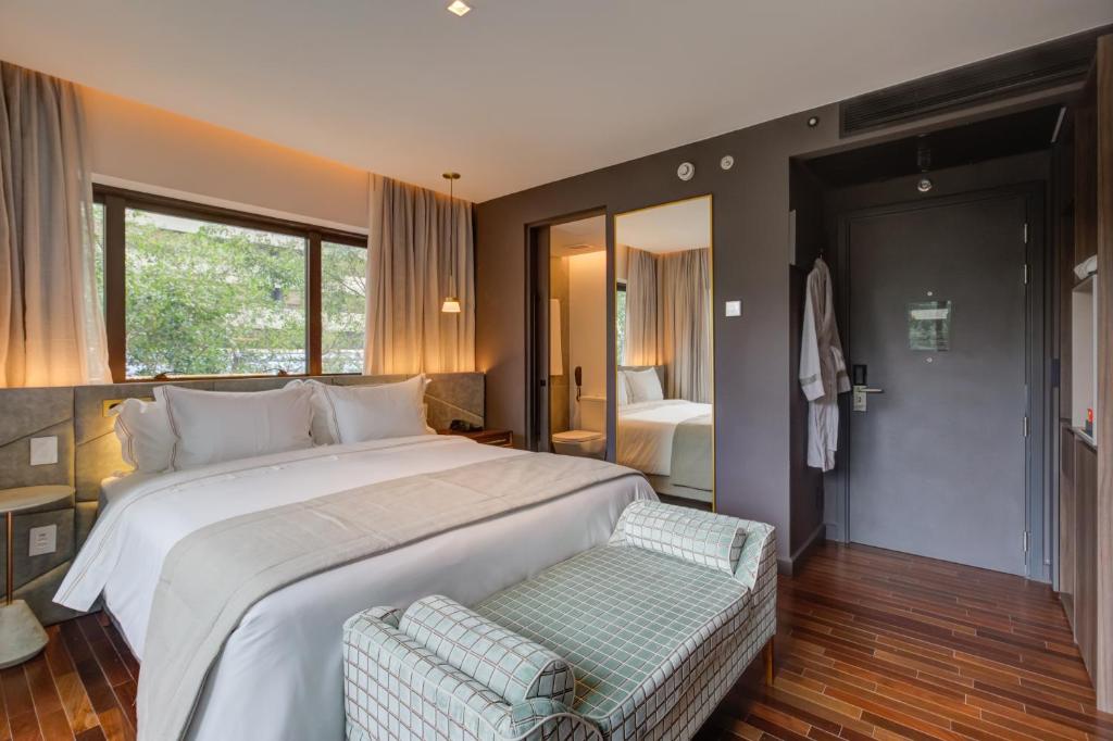 um quarto com uma grande cama branca e uma janela em Qoya São Paulo Paulista, Curio Collection by Hilton em São Paulo