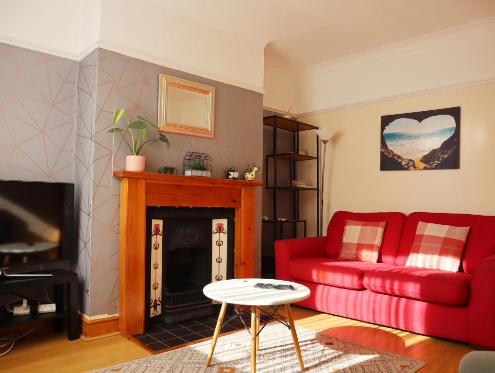 a living room with a red couch and a fireplace at Lovely 3 beds house 6 guests King beds in Sheffield