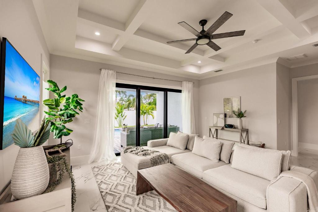 a living room with a white couch and a ceiling fan at Brand New Luxury Naples 4br W Pool By Vanderbilt Beach Coastal Sol By Boutiq in Naples