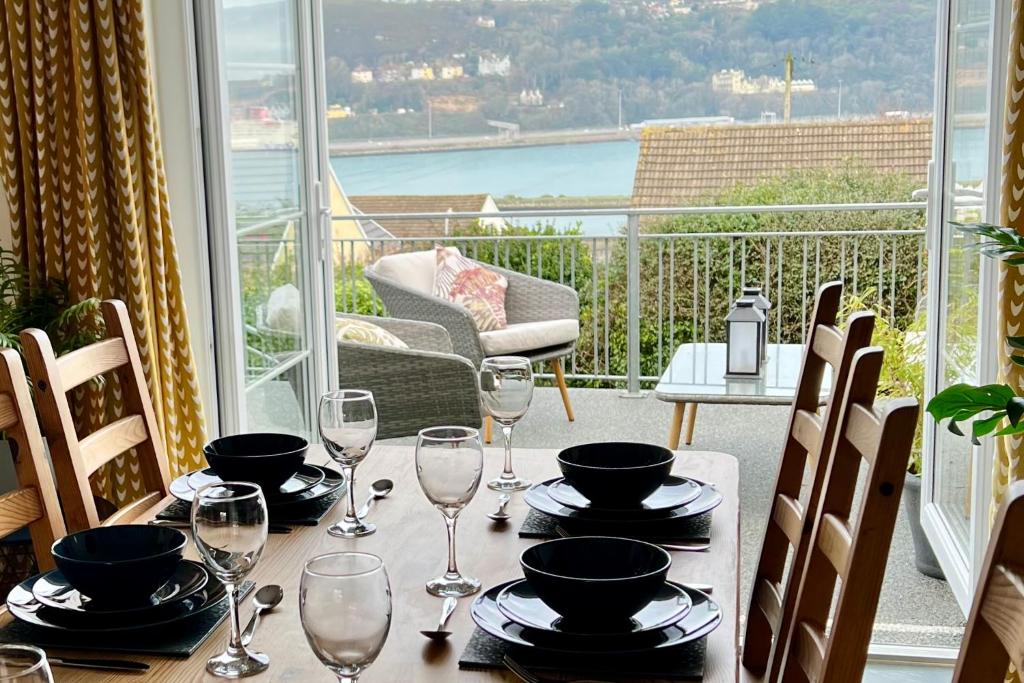 a table with glasses and plates on top of a balcony at The Haven, Fishguard, ideal for Beach, coastal path and town! in Fishguard