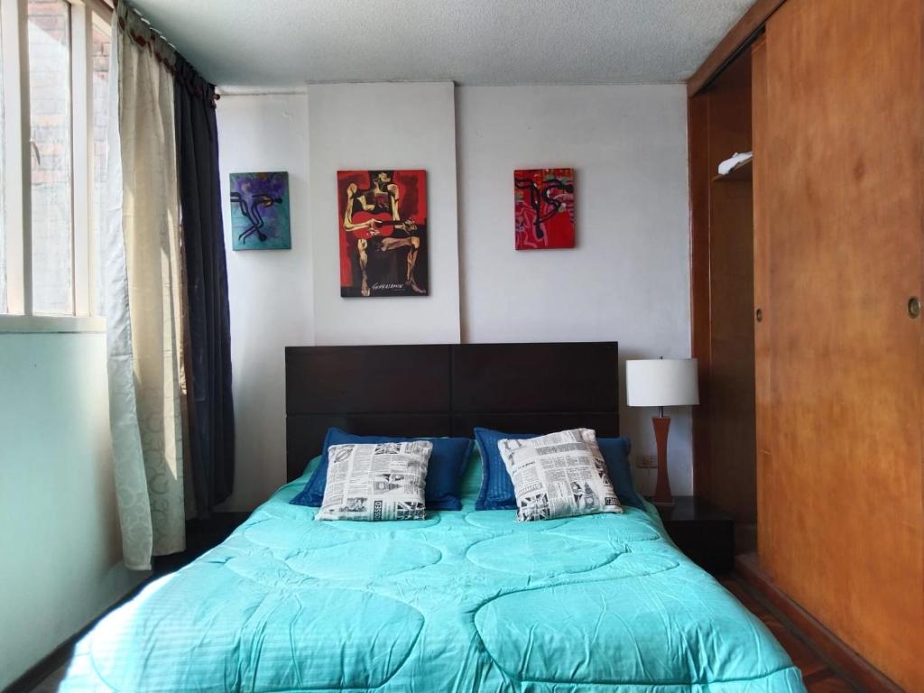 1 dormitorio con 1 cama azul y 2 almohadas en Habitaciones Centro Histórico, en Bogotá