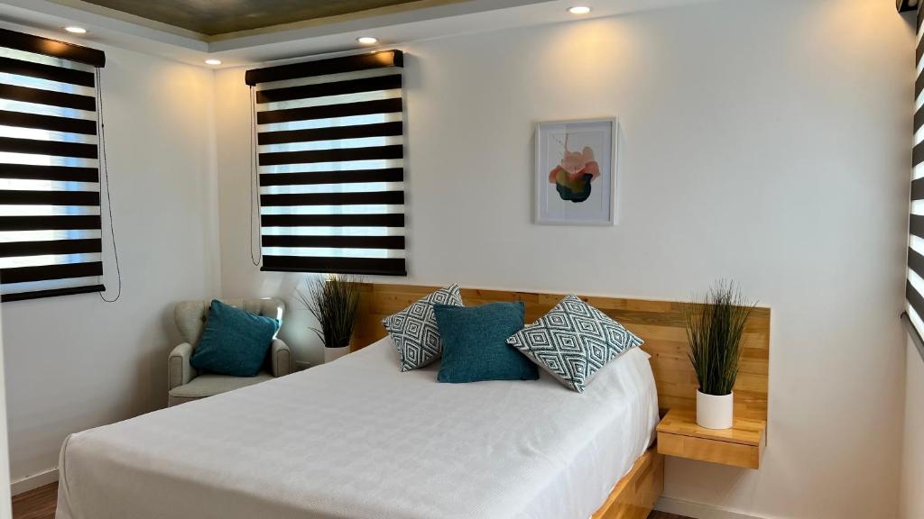 a bedroom with a white bed with blue pillows at Baja Suites - Departamentos Vacacionales in Ensenada