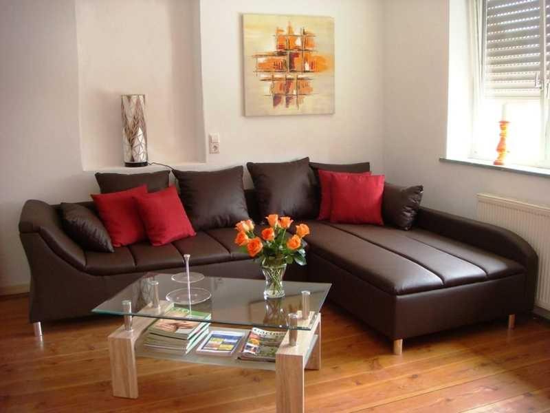 a living room with a brown leather couch with red pillows at Klaschter Gastewohnung in Groß-Umstadt