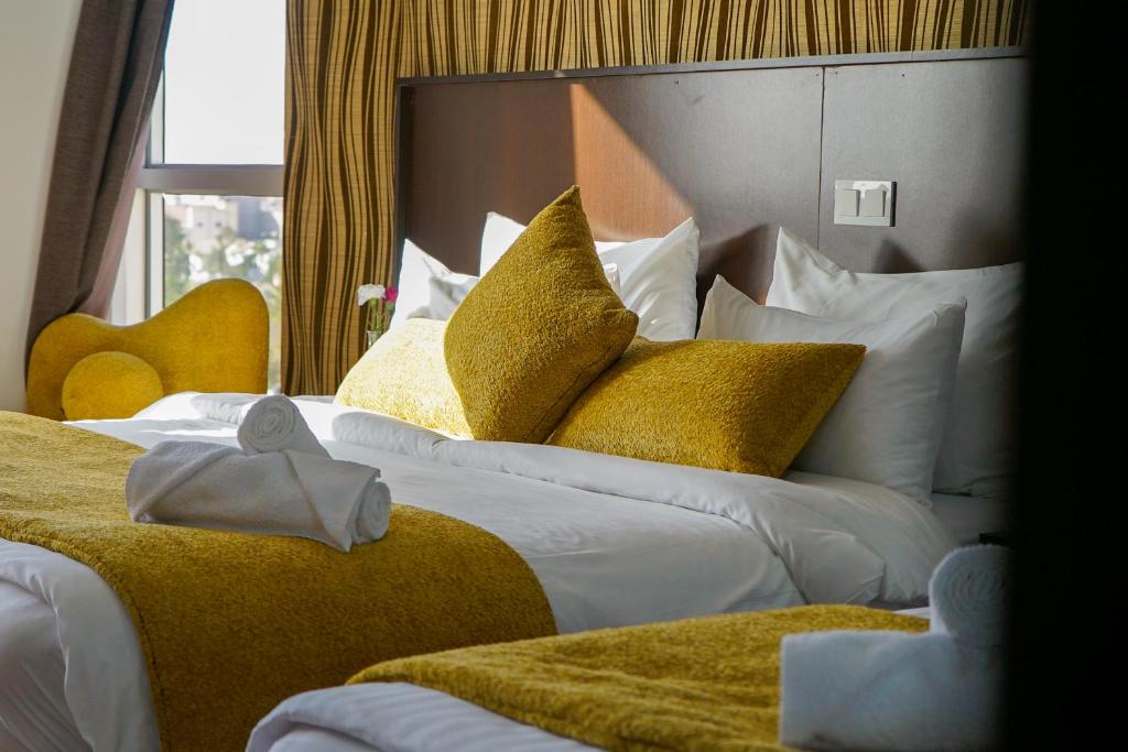 um quarto de hotel com duas camas com almofadas amarelas e brancas em Sahariano hotel City Center em Laayoune