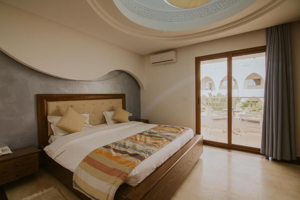 a bedroom with a large bed and a large window at Palm Djerba Suites in Mezraya