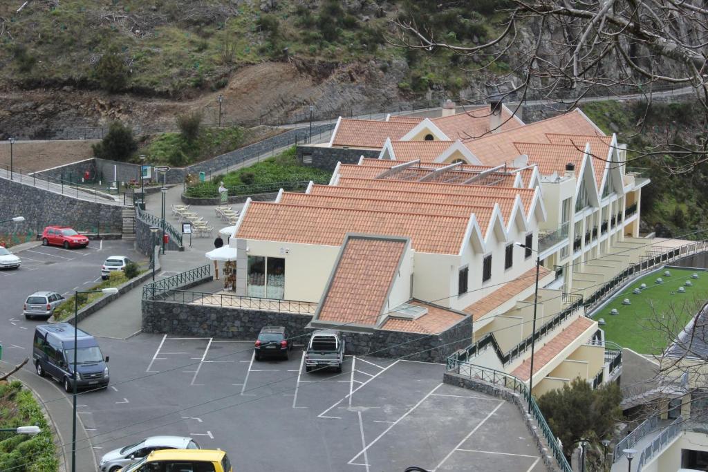 een gebouw met veel auto's geparkeerd op een parkeerplaats bij Eira do Serrado - Hotel & Spa in Curral das Freiras