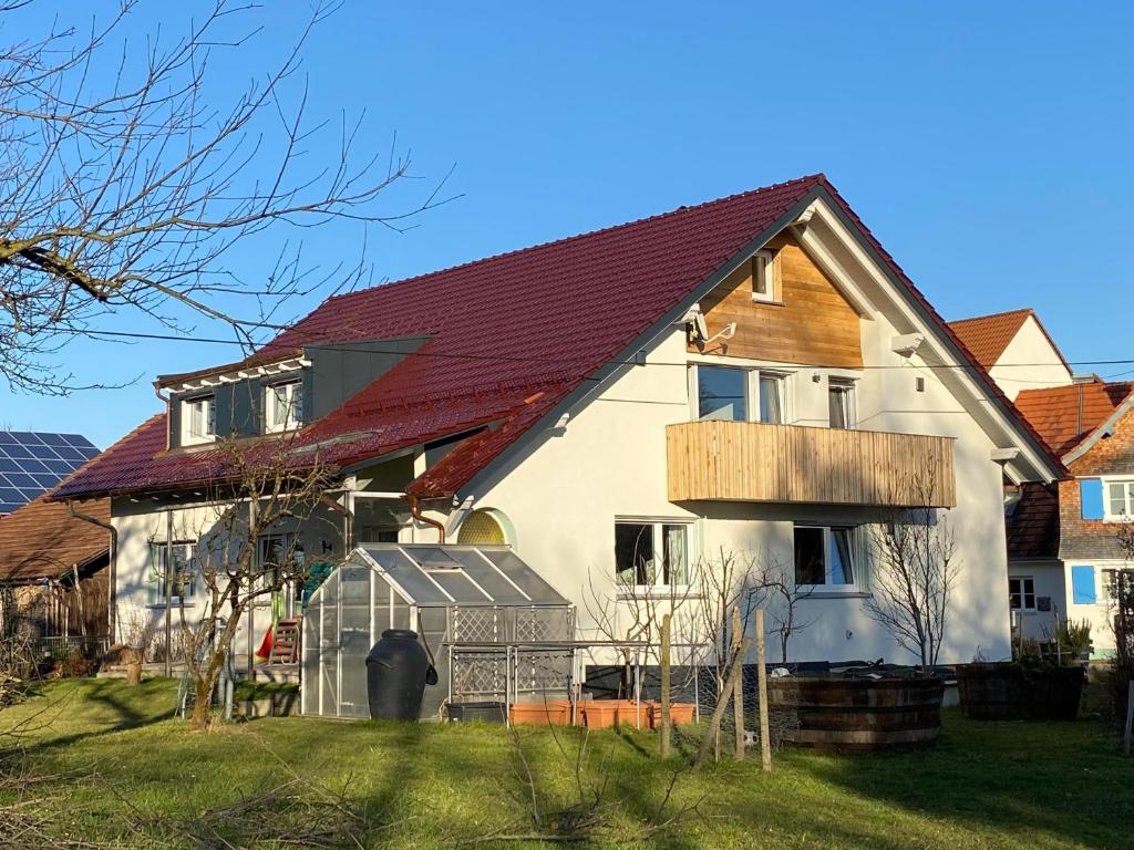 une grande maison avec un toit rouge dans l'établissement Ferienwohnung im Obstgarten, à Achberg