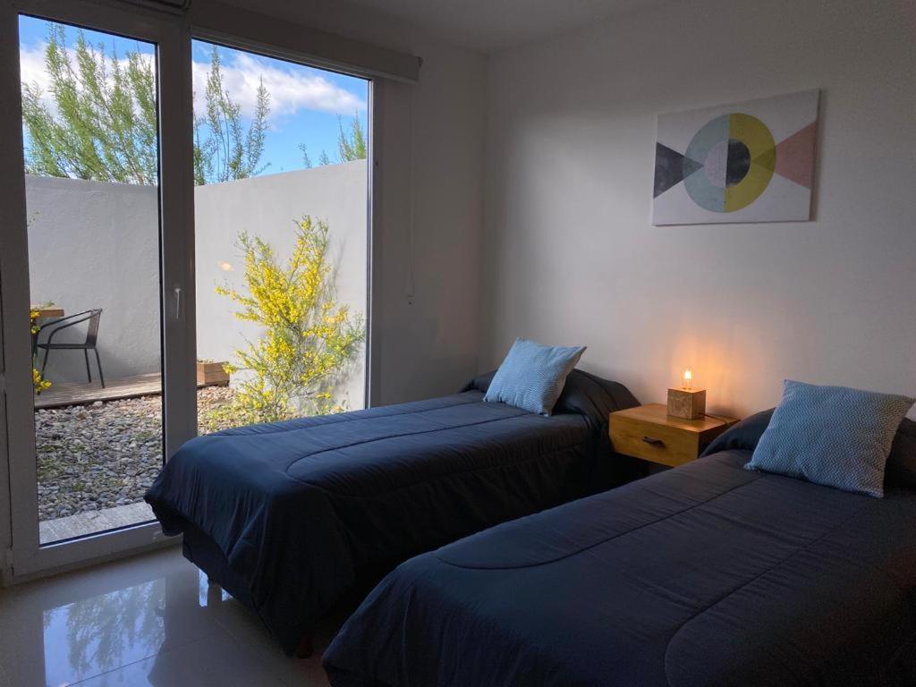 a bedroom with two beds and a large window at Penguins Flats 4 in Ushuaia