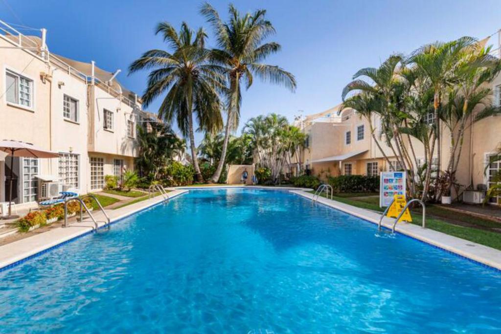 a large swimming pool with palm trees and buildings at Nuevo en Booking Casa Acapulco Diamante a Pasos de la Playa in Acapulco