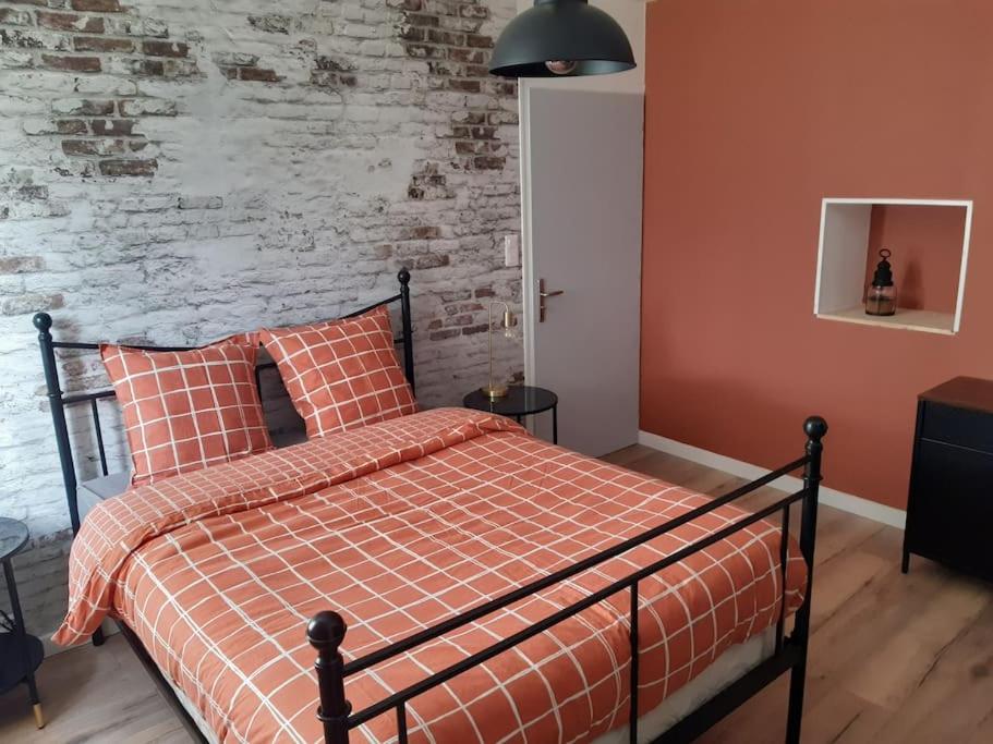 um quarto com uma cama e uma parede de tijolos em Maisonnette avec jardin 