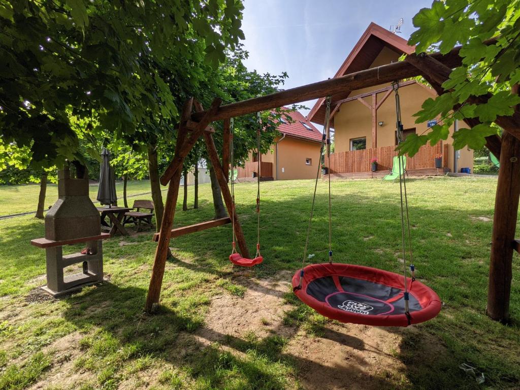 une balancelle rouge sous un arbre dans une cour dans l'établissement Gajówka, à Radków