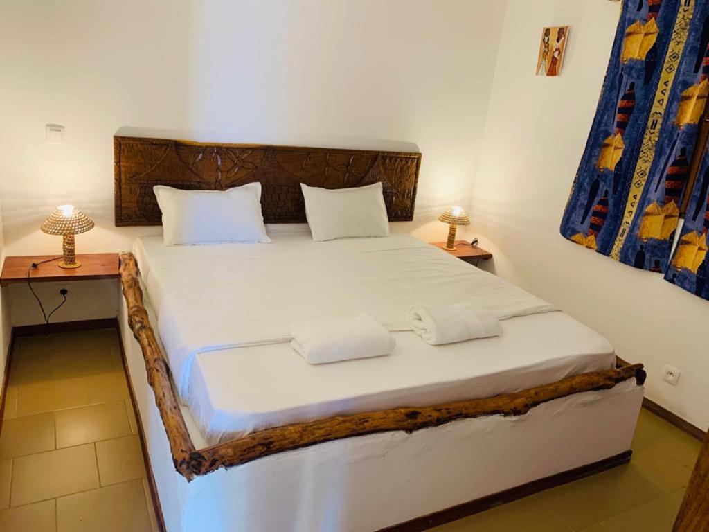 a bedroom with a large white bed with two tables at Villa Nemocotier in Cap Skirring