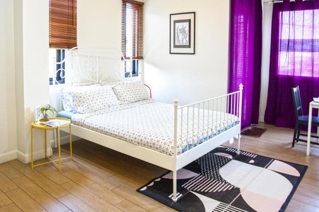 a bedroom with a white bed and purple curtains at 26bed and coffee in Ban Rong Khoei